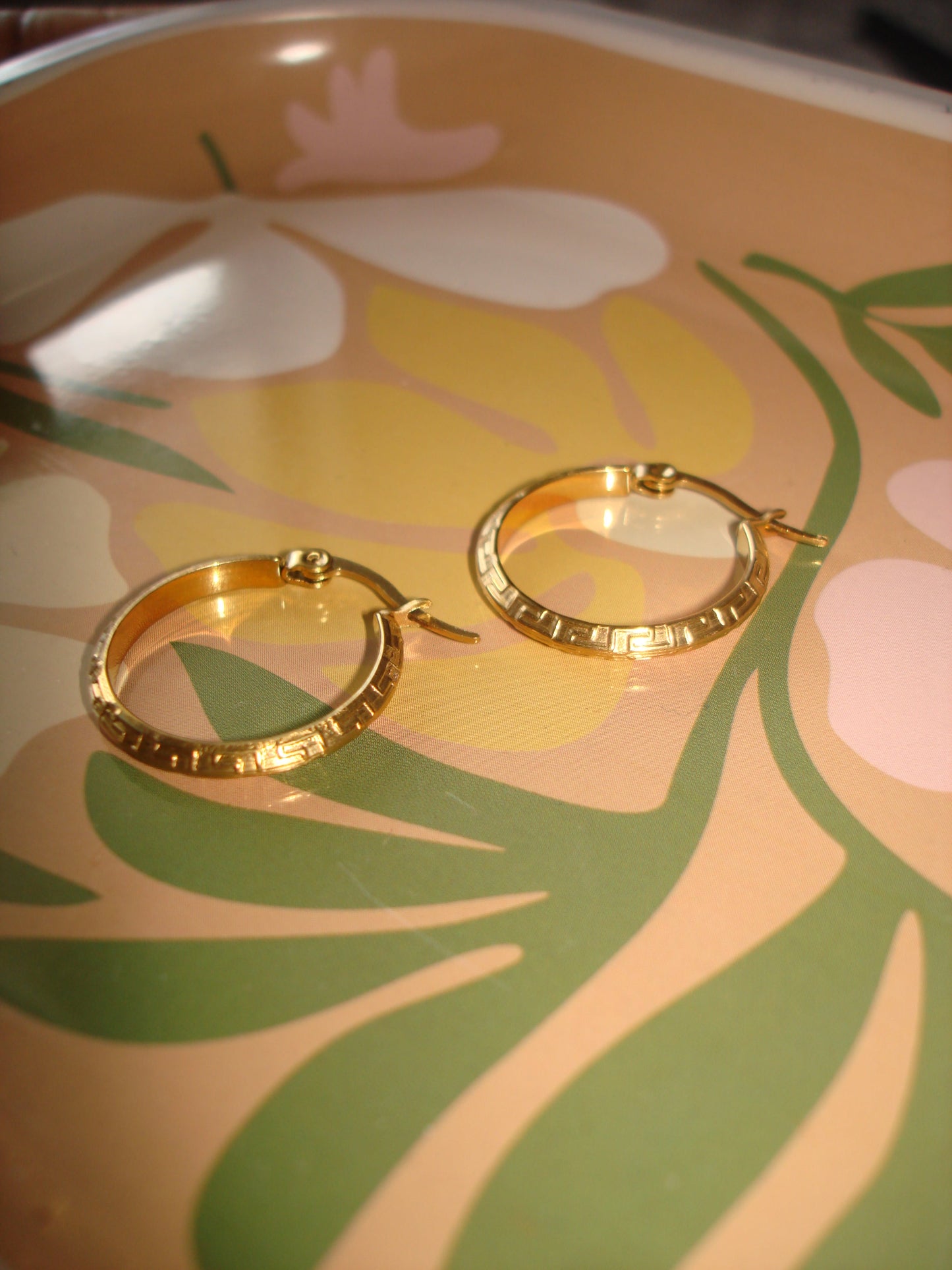 Gold hoop earrings on a floral-patterned surface
